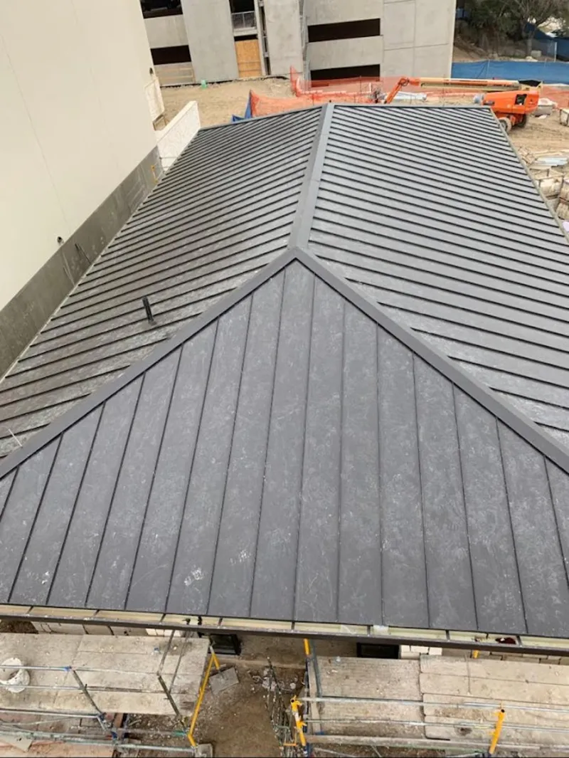 Commercial metal roof construction with crane equipment in Southborough